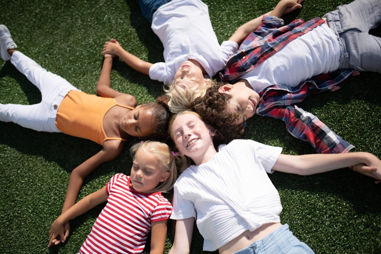 Children laughing while lying on the grass on a sunny day