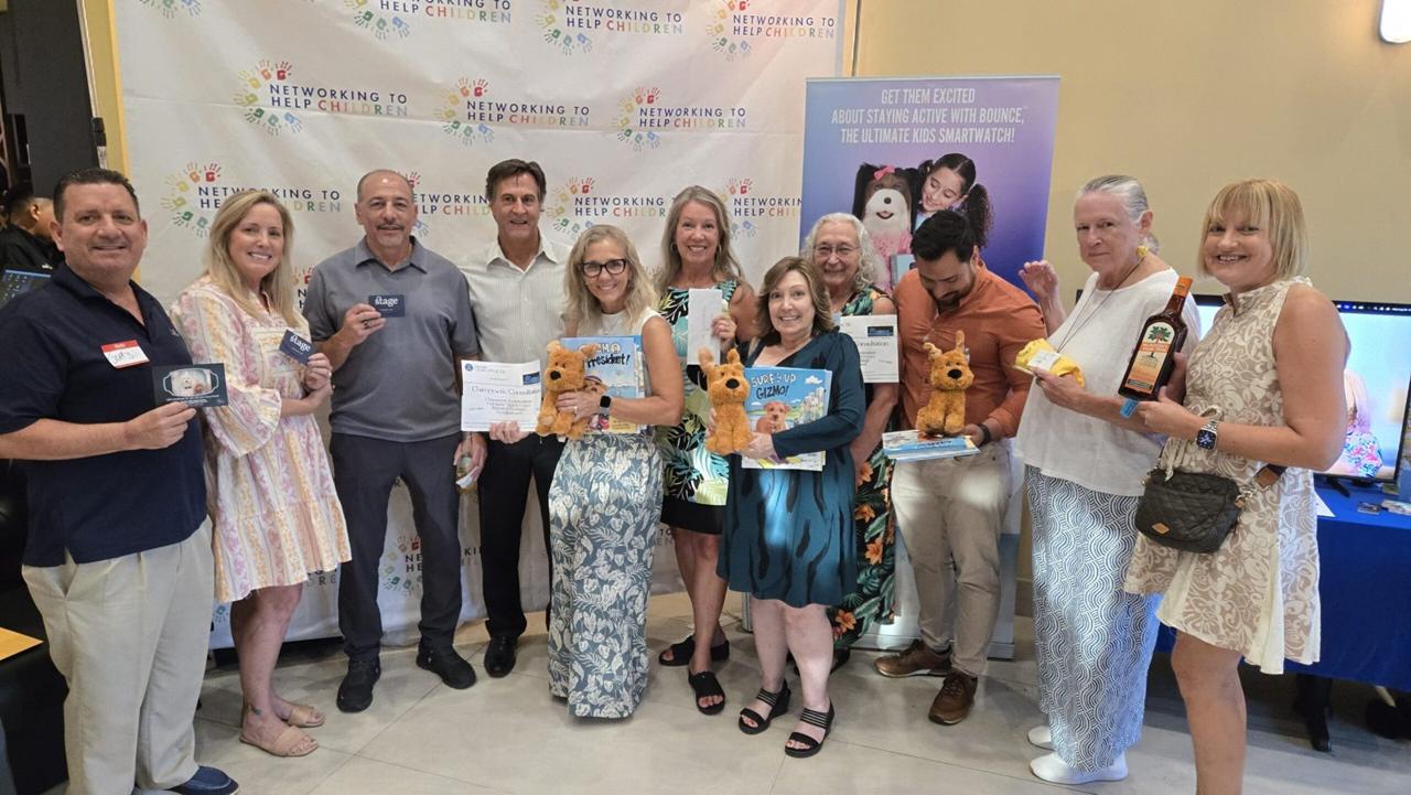 Guests at a Networking To Help Children event with a check presentation on stage